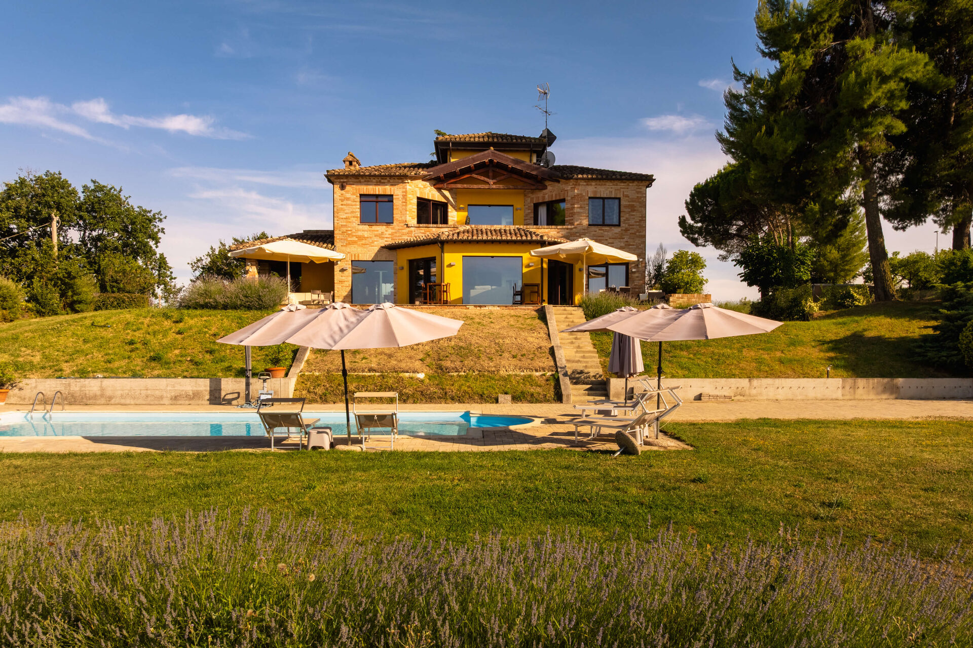 Facciata della villa con lavanda e piscina al tramonto